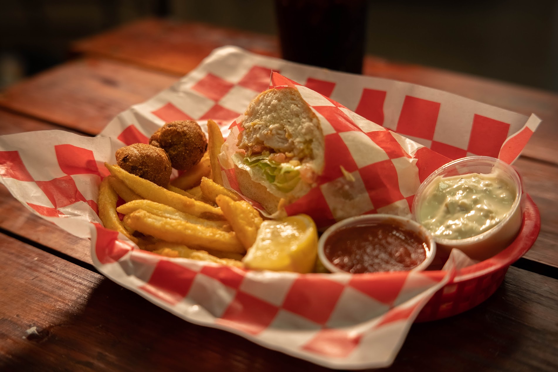 Po'boy basket with fries and hush puppies in a red checkered basket