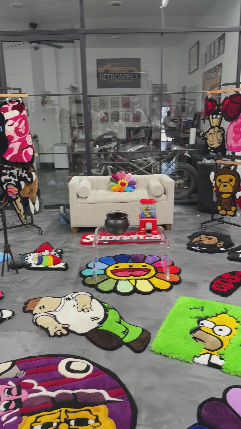The Highoffrugz studio floor covered in hand-tufted rugs — a Murakami flower, Homer Simpson, a Supreme box logo and more