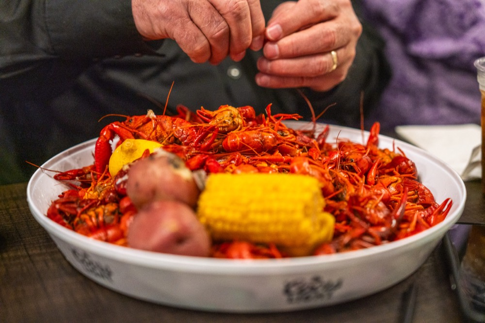 A guest peeling crawfish at the table